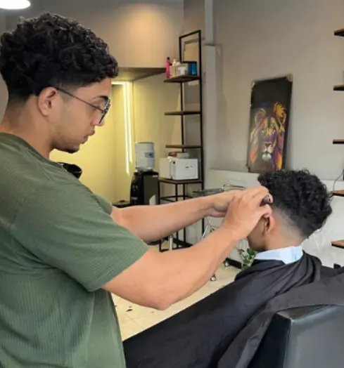 Mateus realizando um corte de cabelo na Espaço Muniz Barbearia