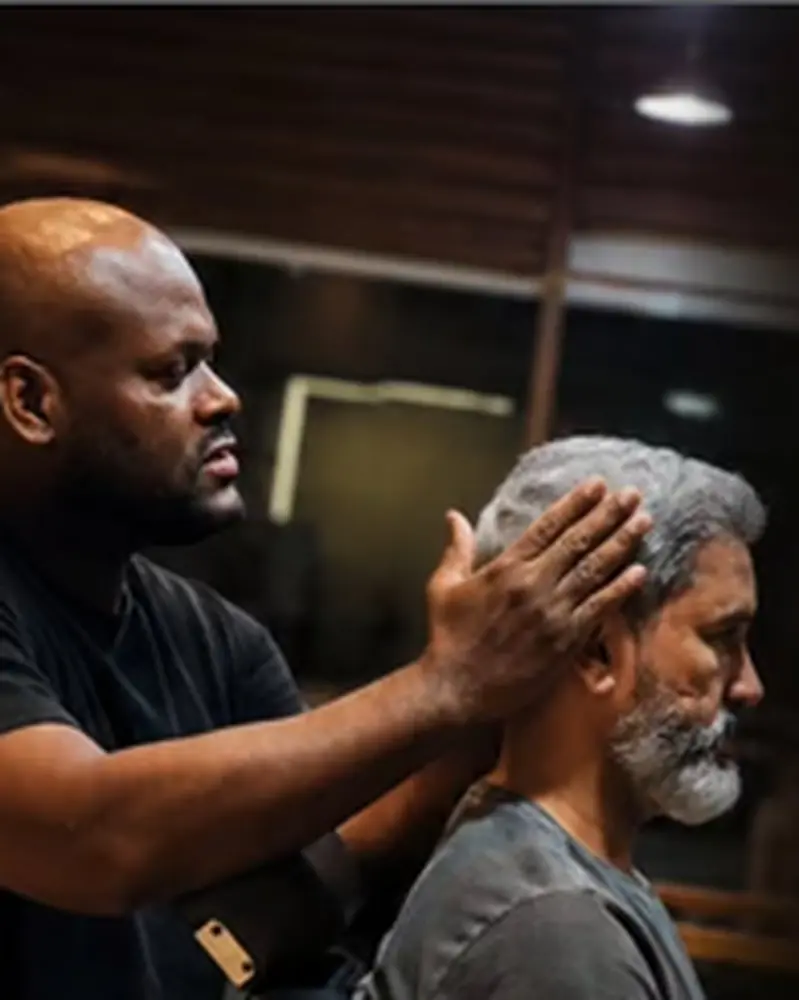 Profissional avaliando cabelo e formato do rosto durante atendimento de visagismo.